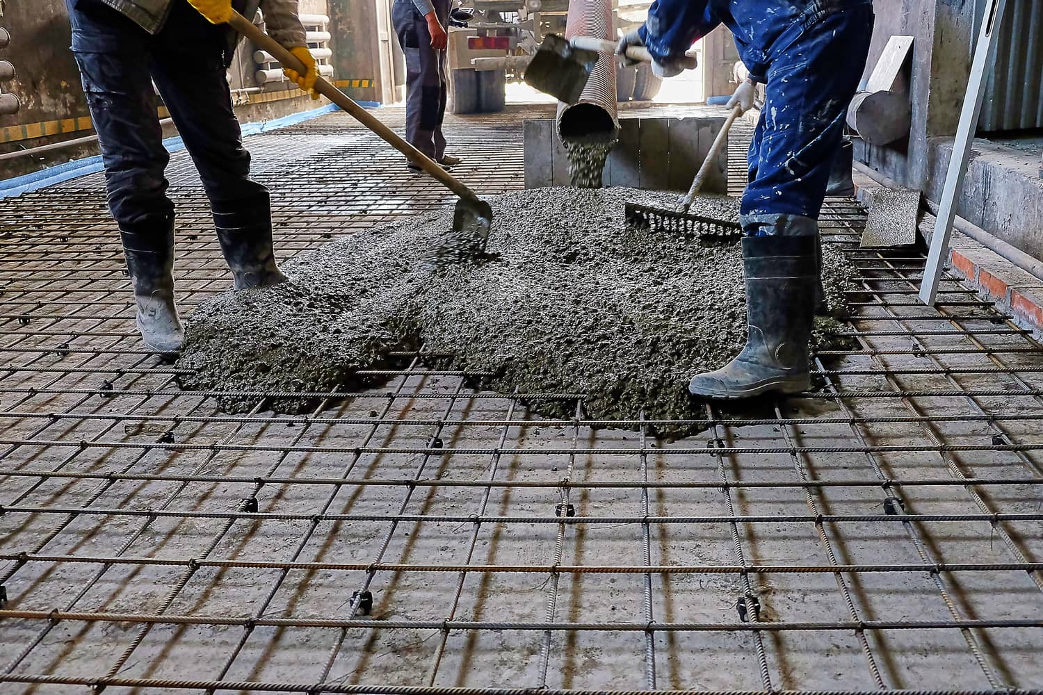 This is an image of two contractors distributing poured cement with a rake.