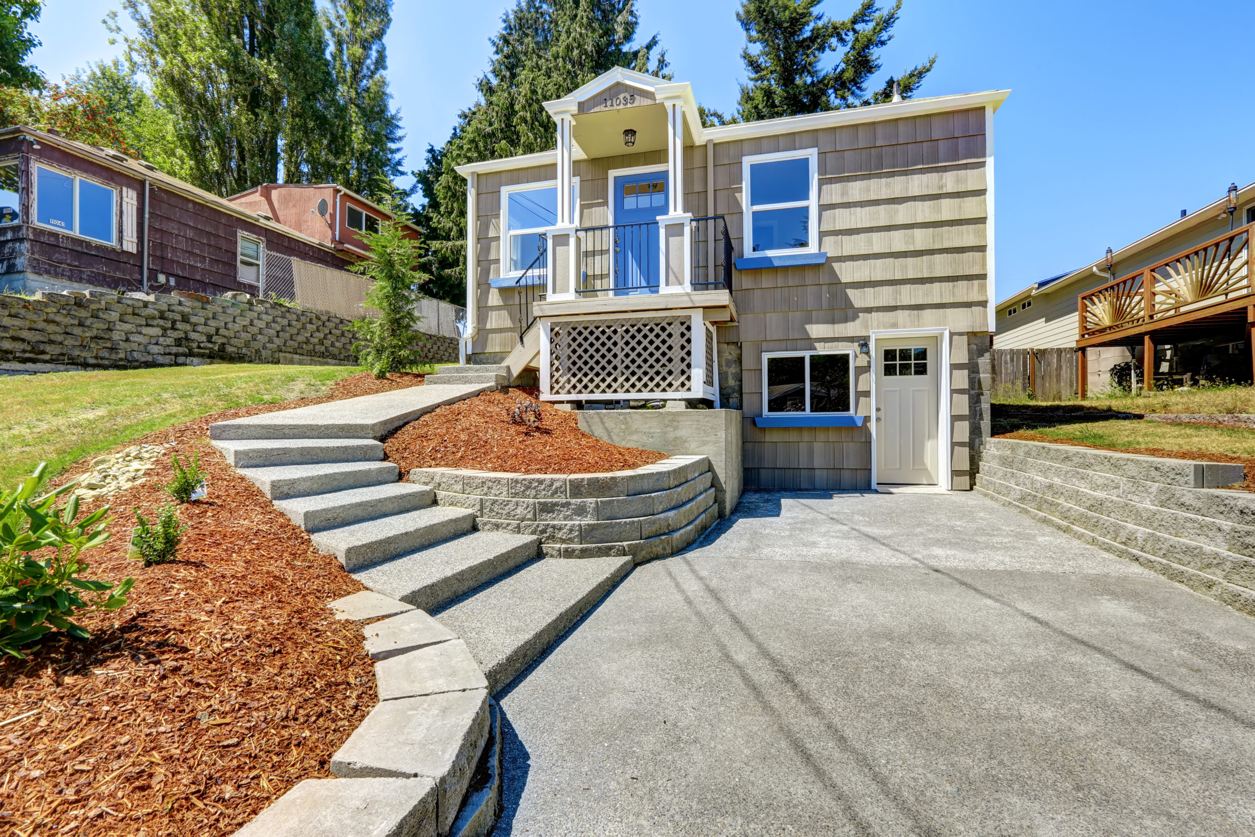 This is an image of a residential property with a concrete driveway and stairs.